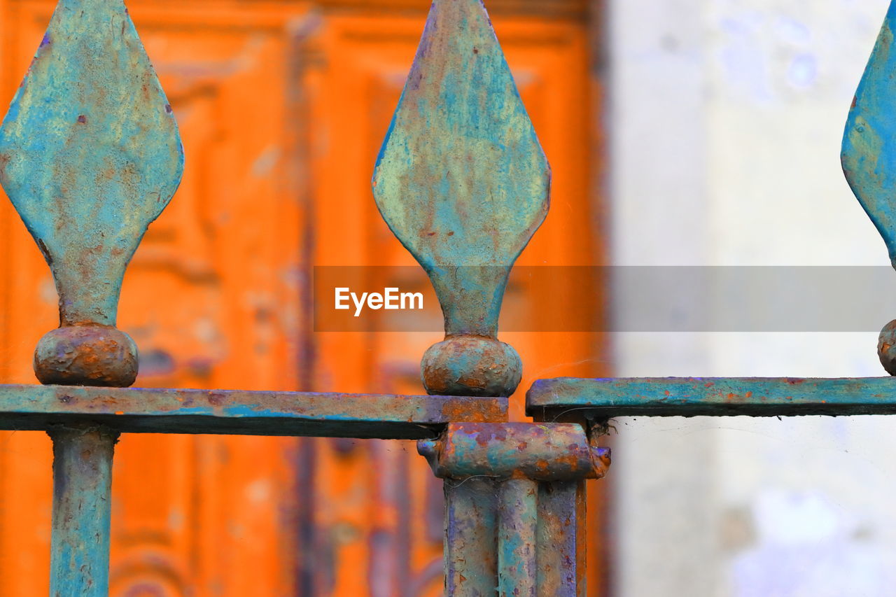 CLOSE-UP OF RUSTY METAL FENCE AGAINST GATE