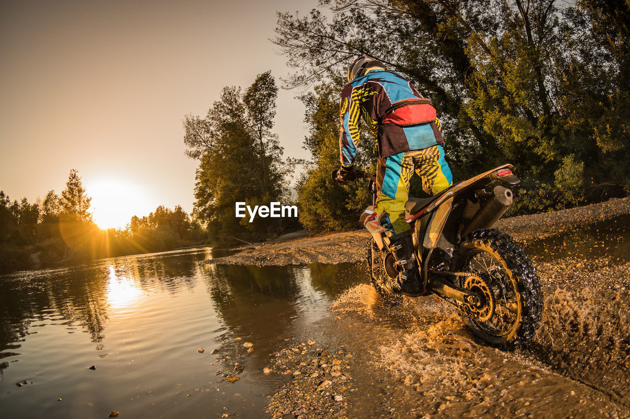 MAN RIDING BICYCLE IN WATER AGAINST SKY