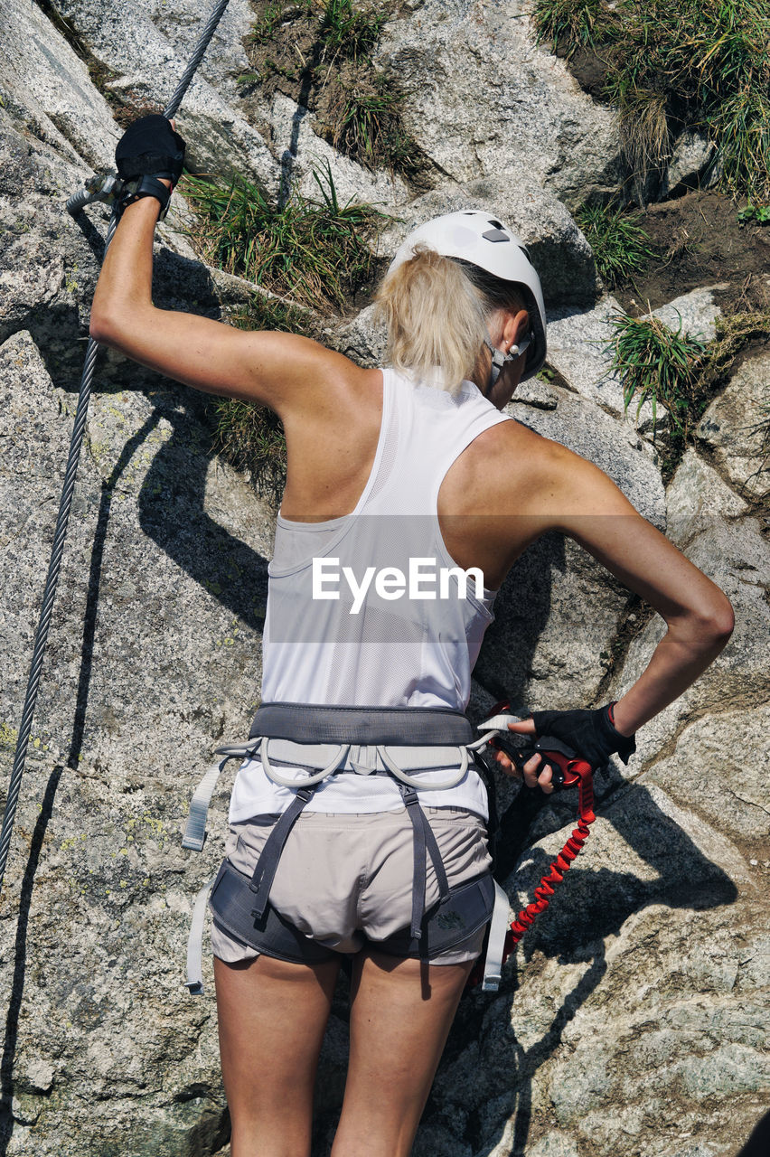 Rear view of young woman climbing rock