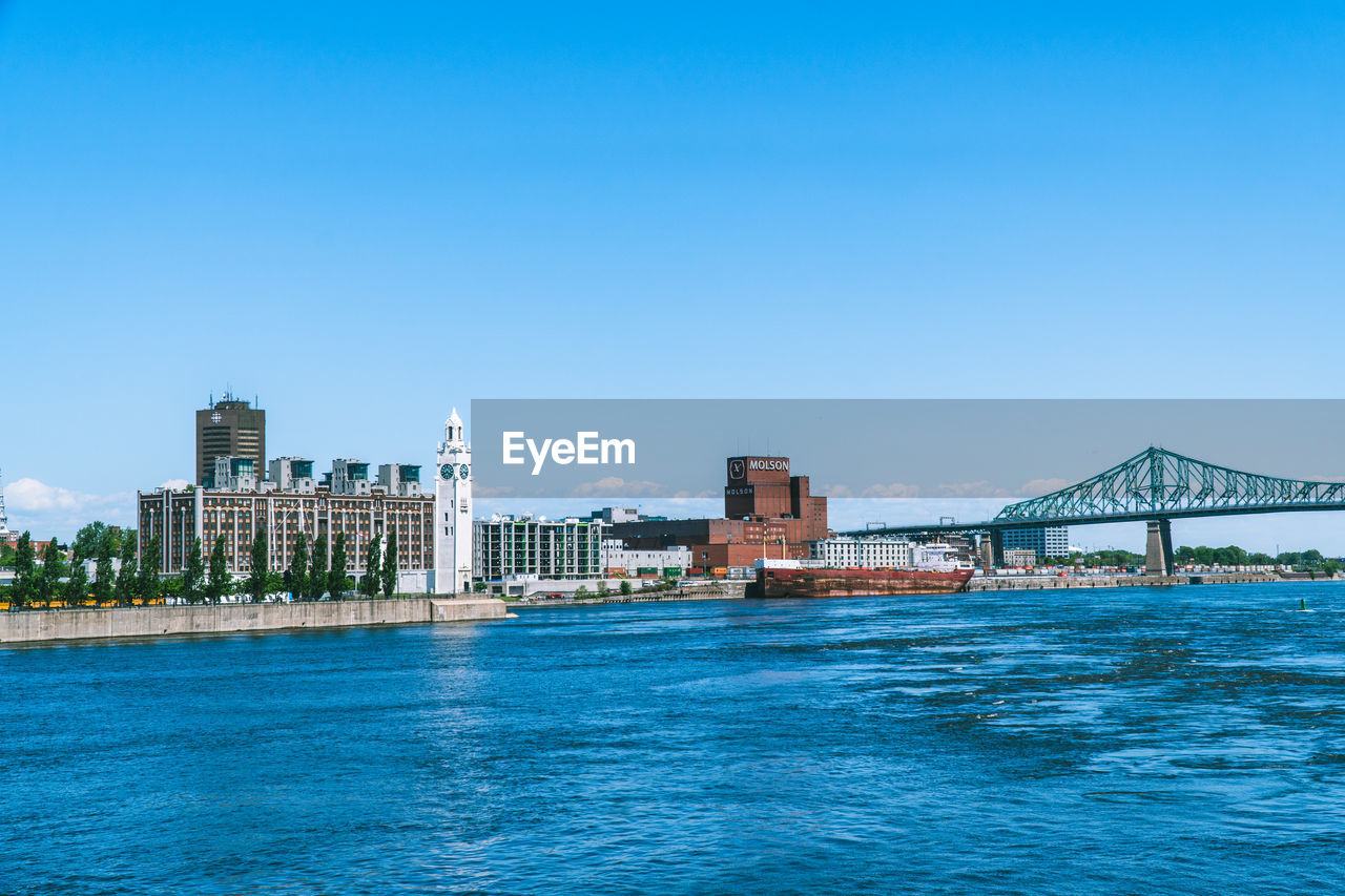 View of buildings at waterfront against blue sky