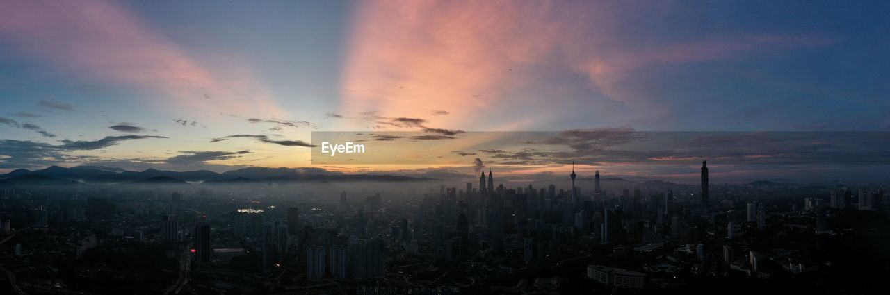 View of city against cloudy sky during sunset