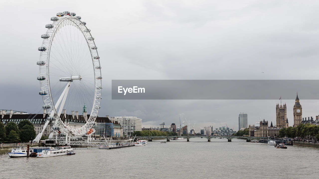 FERRIS WHEEL IN CITY AGAINST CLOUDY SKY