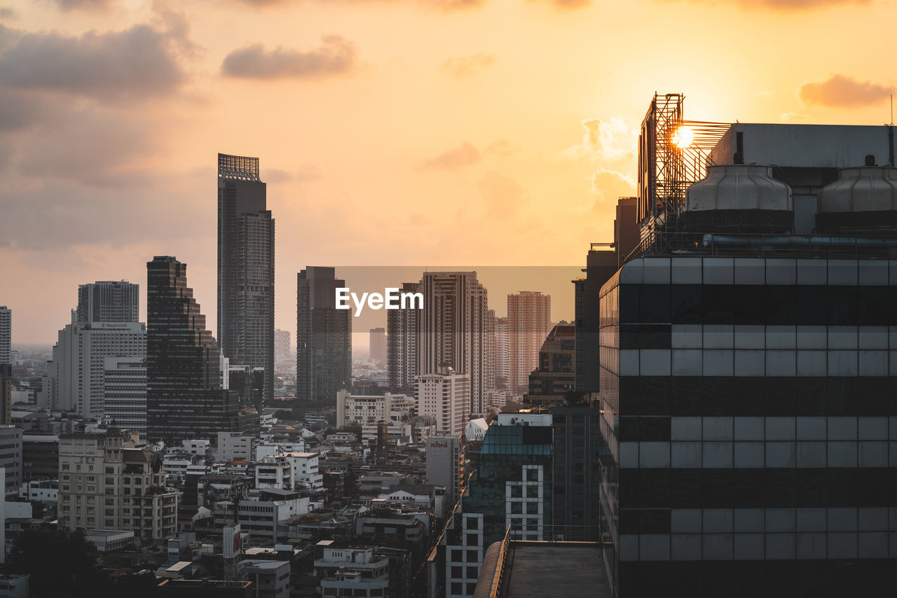 Modern buildings in city against sky during sunset