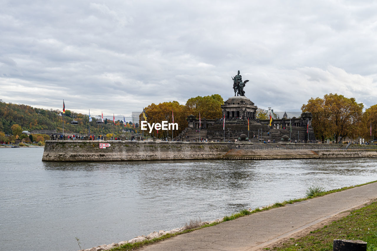 bridge over river against cloudy sky