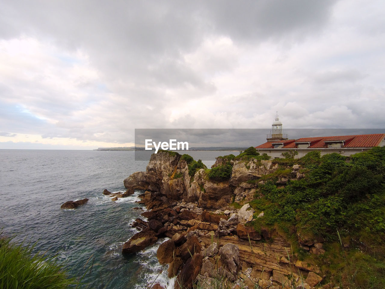 View of the seaside with a lighthouse over a cliff on a cloudy day. taken in santander, spain