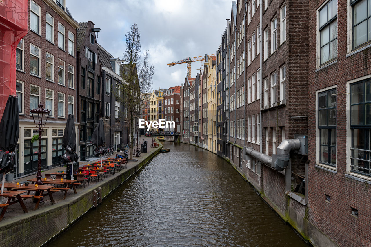 Canal amidst buildings in city against sky