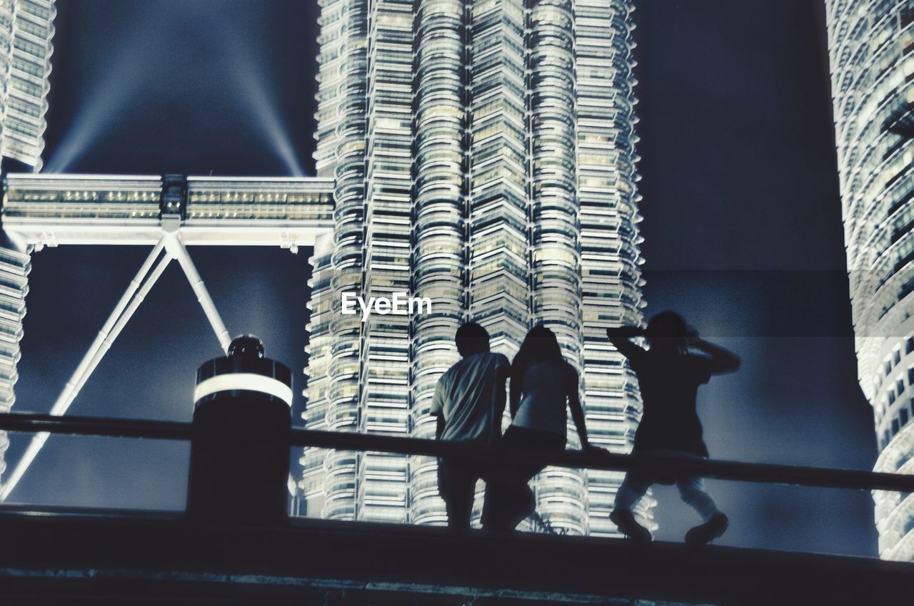 LOW ANGLE VIEW OF MEN STANDING AT MODERN OFFICE BUILDING