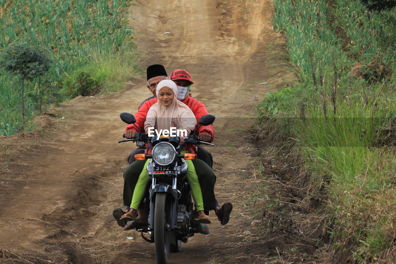 REAR VIEW OF MAN RIDING MOTORCYCLE ON ROAD