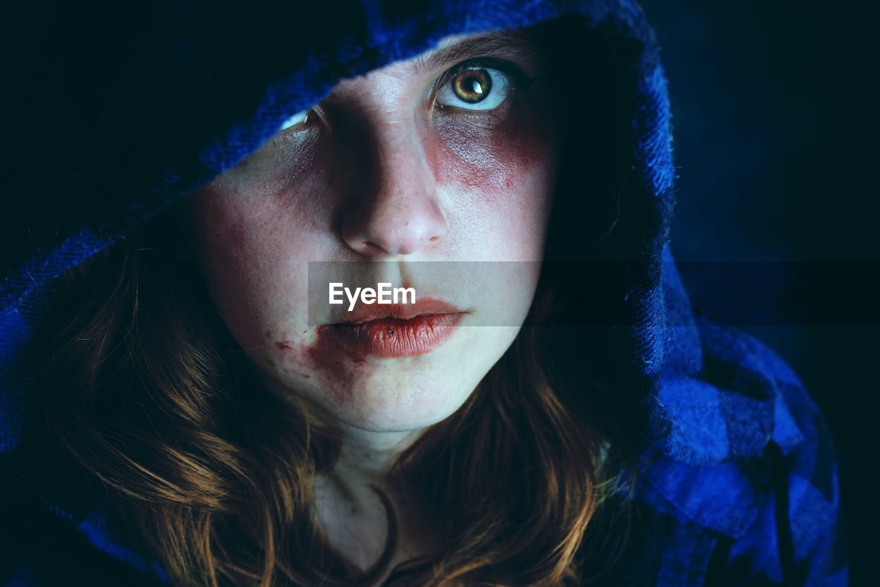 Close-up portrait of injured woman wearing blue hooded shirt