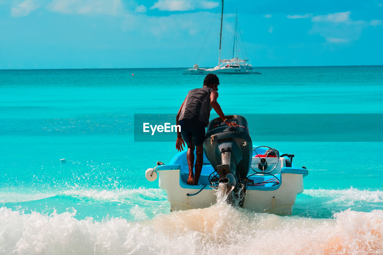 Rear view of man in motorboat against sky