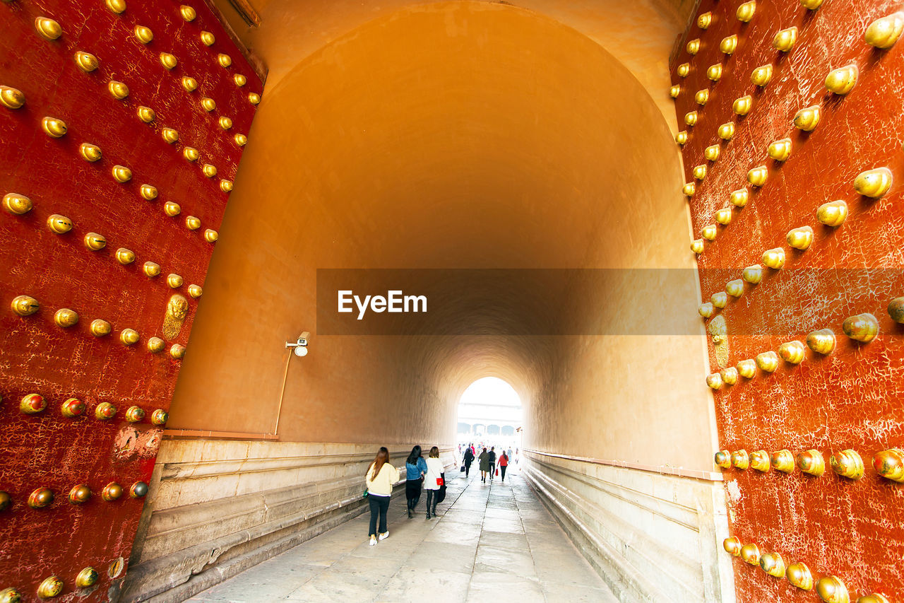 Rear view of people walking in tunnel