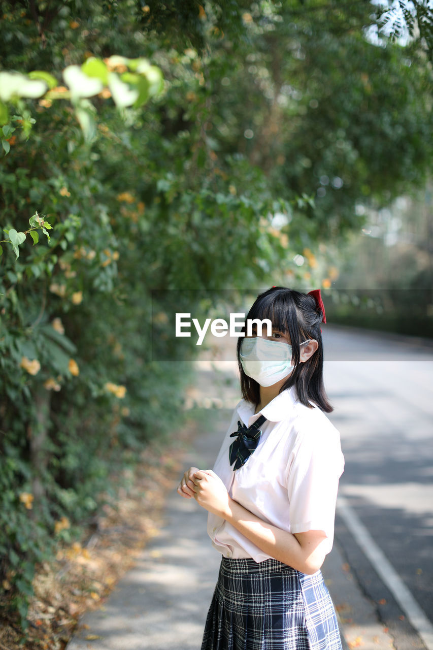 Portrait of young woman wearing mask standing outdoors