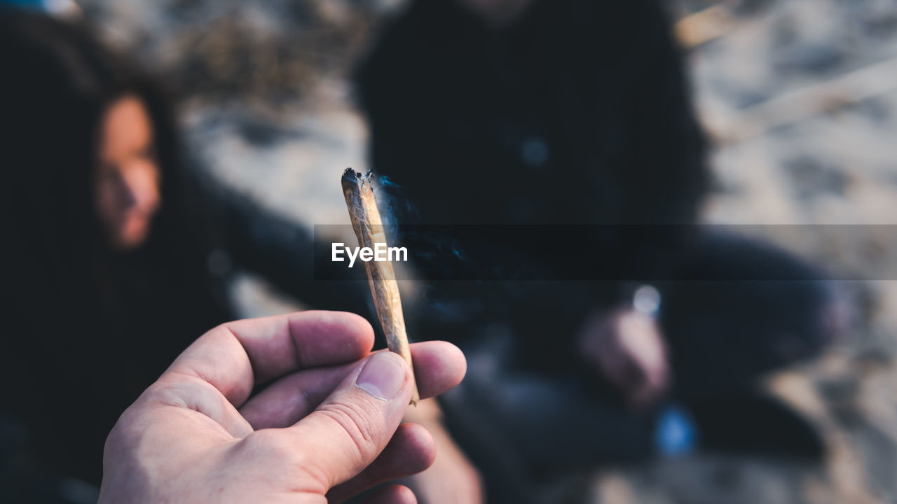 Cropped hand of woman smoking marijuana joint in city