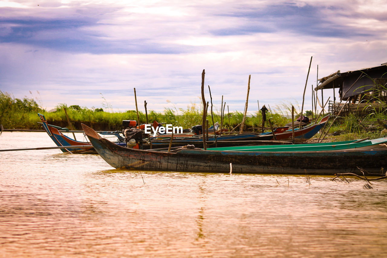 Boats moored at harbor against sky