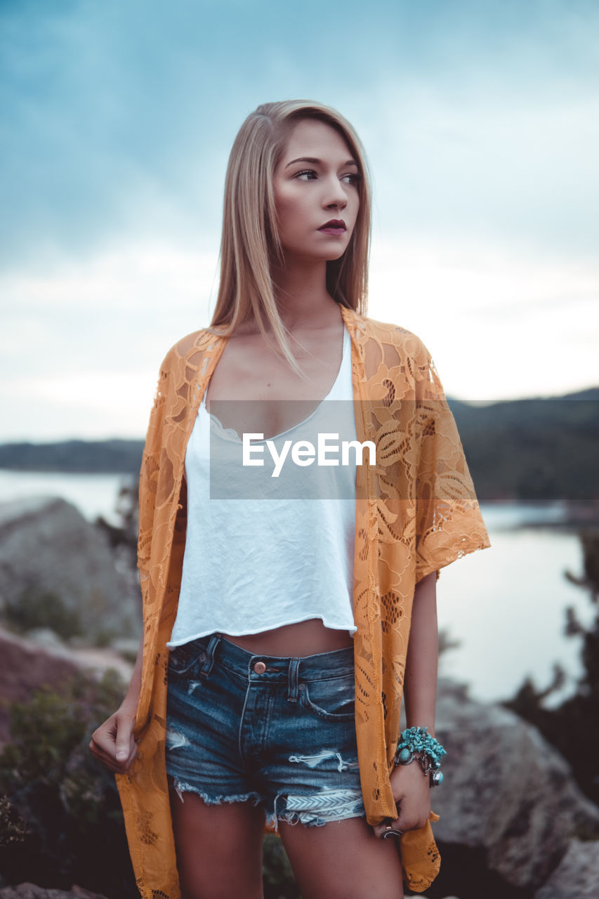 Beautiful young woman standing against sky