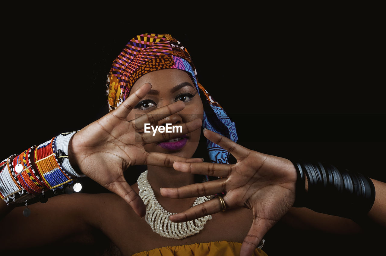 Portrait of woman wearing costume gesturing while standing against black background