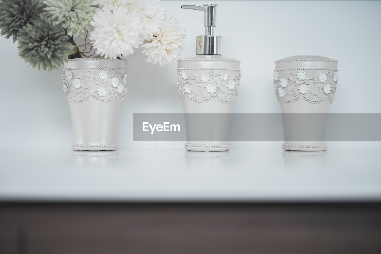 CLOSE-UP OF WHITE FLOWERS IN GLASS VASE ON TABLE