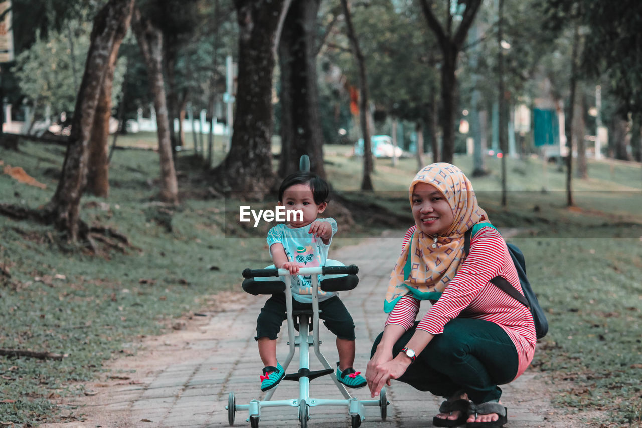 Full length portrait of mother with daughter on footpath at park