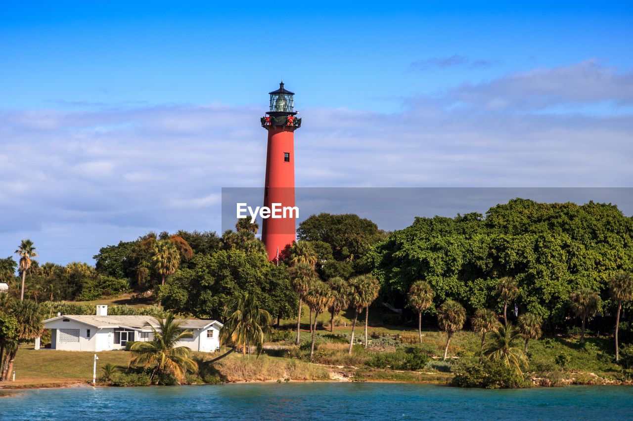 LIGHTHOUSE BY SEA AGAINST BUILDINGS