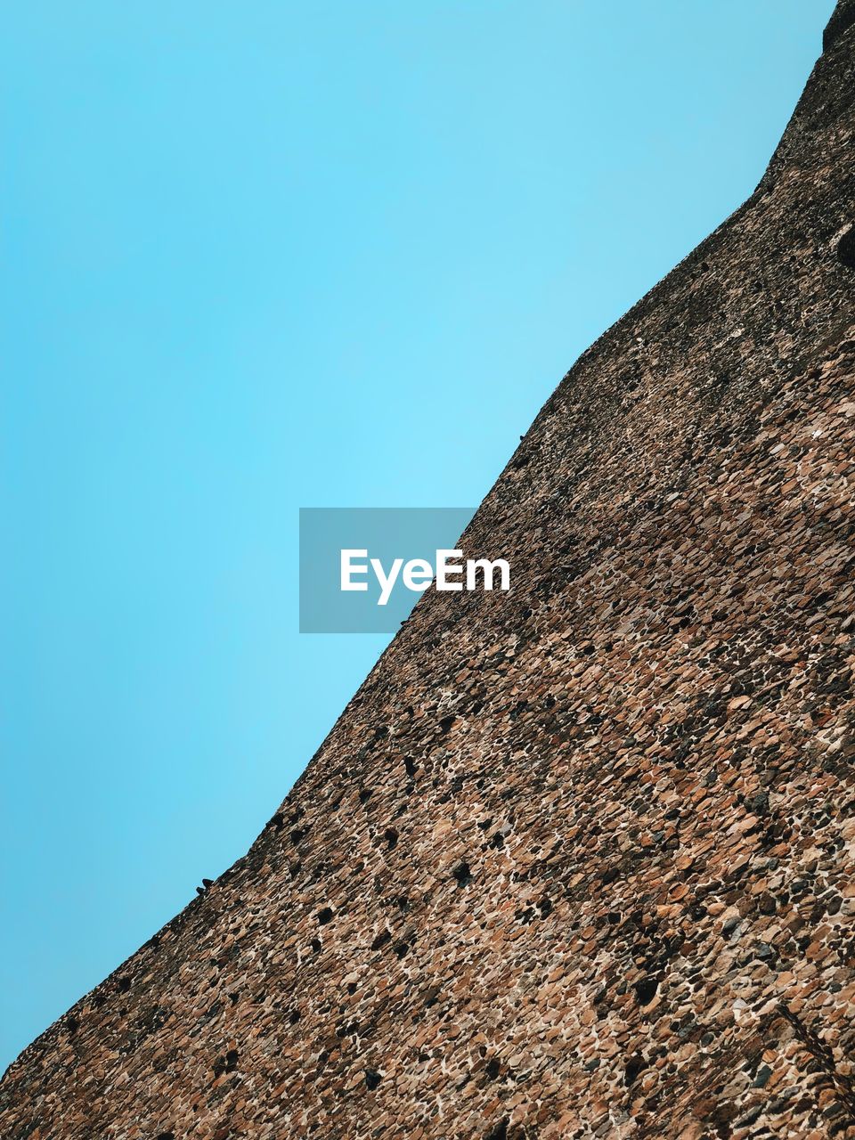 LOW ANGLE VIEW OF WALL AGAINST CLEAR BLUE SKY