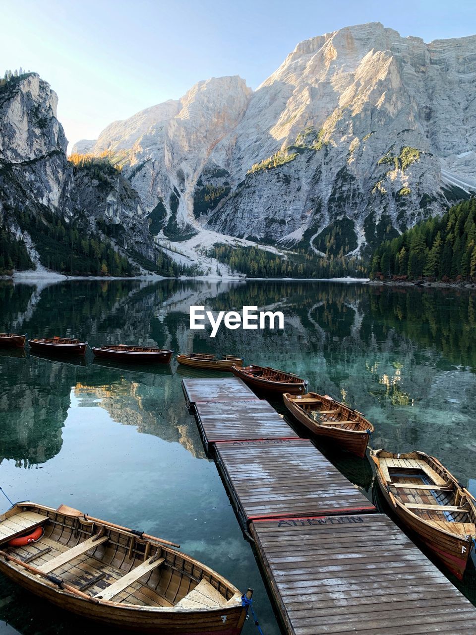 Boats moored by pier in lake against mountains