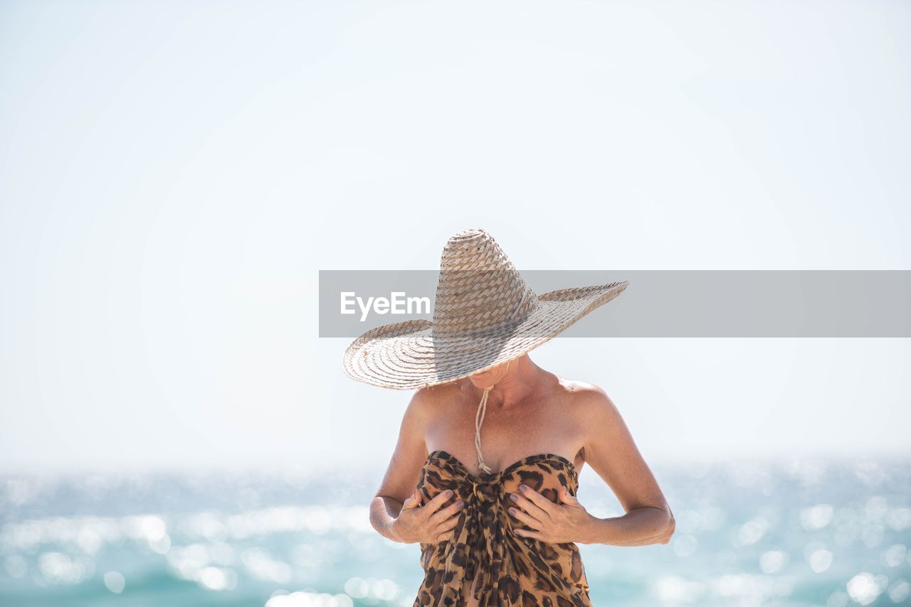 Woman wearing hat at beach against sky