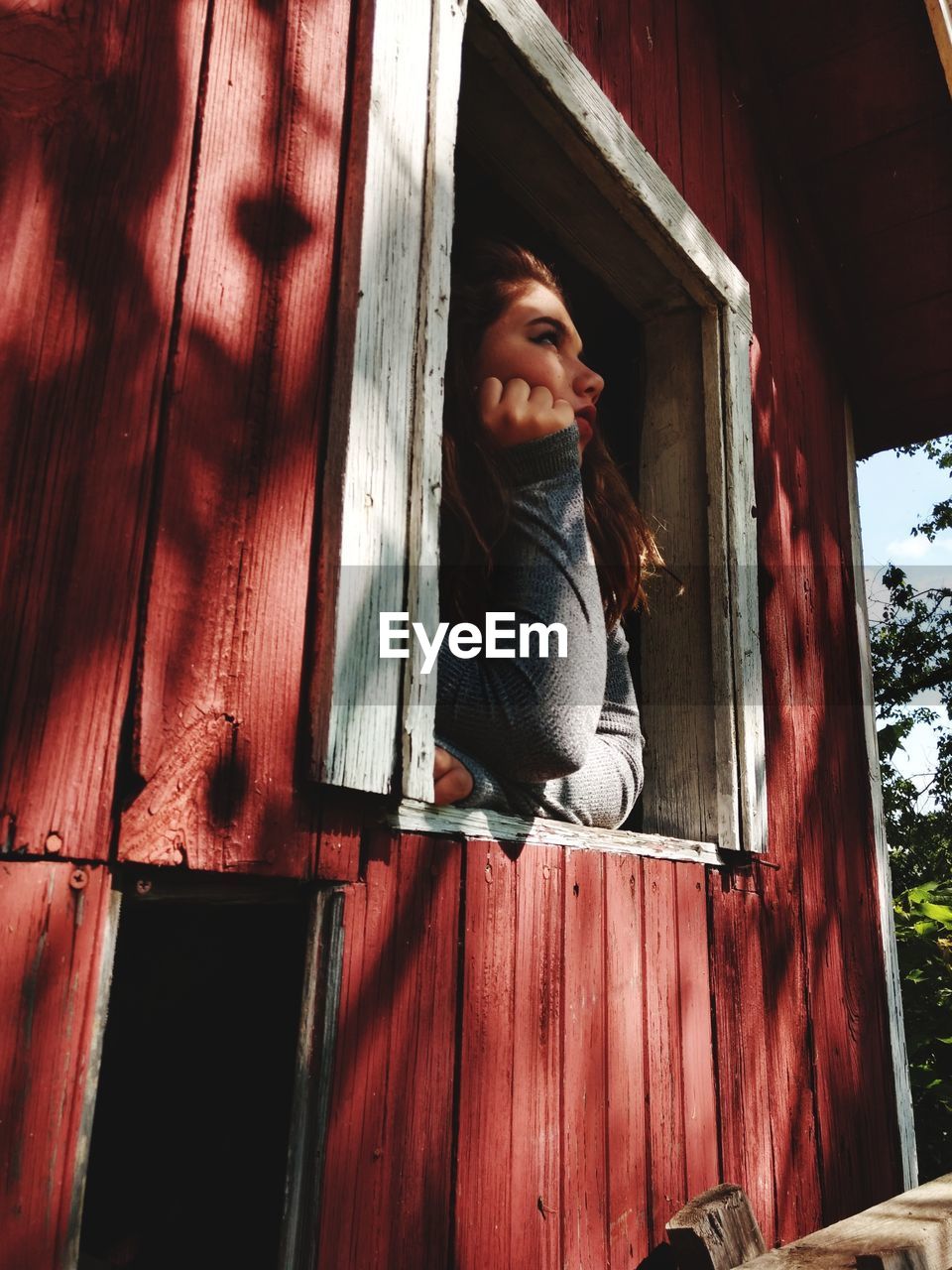 Low angle view of woman leaning on window