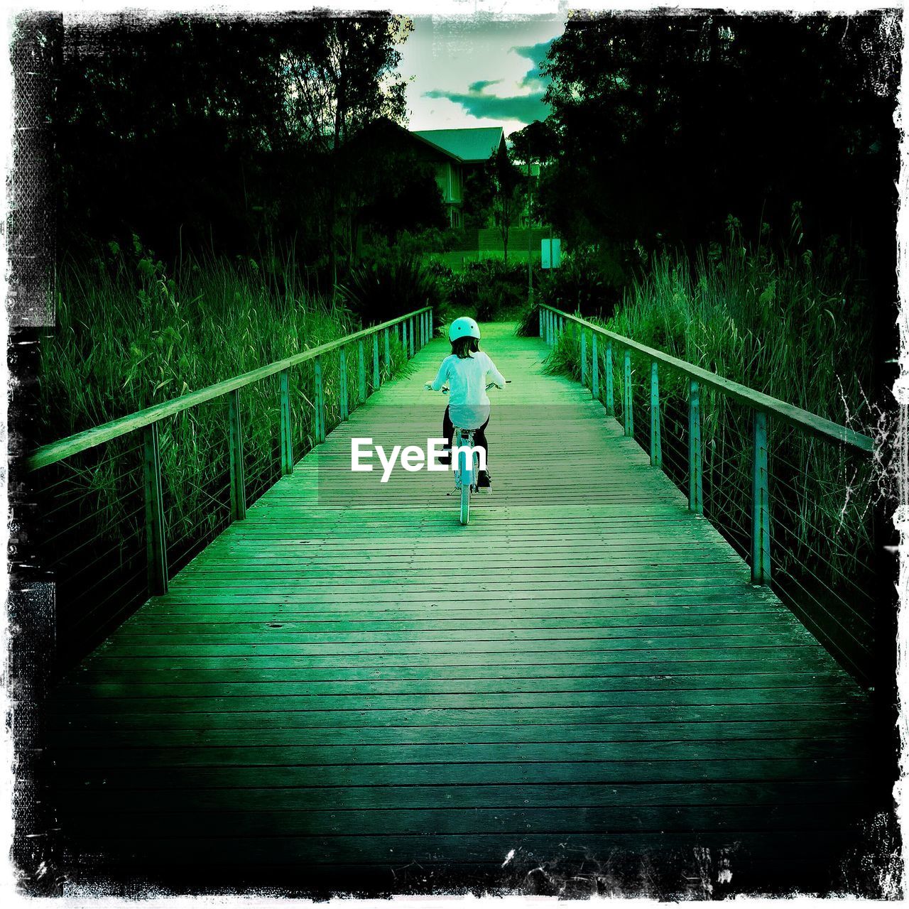 REAR VIEW OF WOMAN WALKING ON FOOTBRIDGE