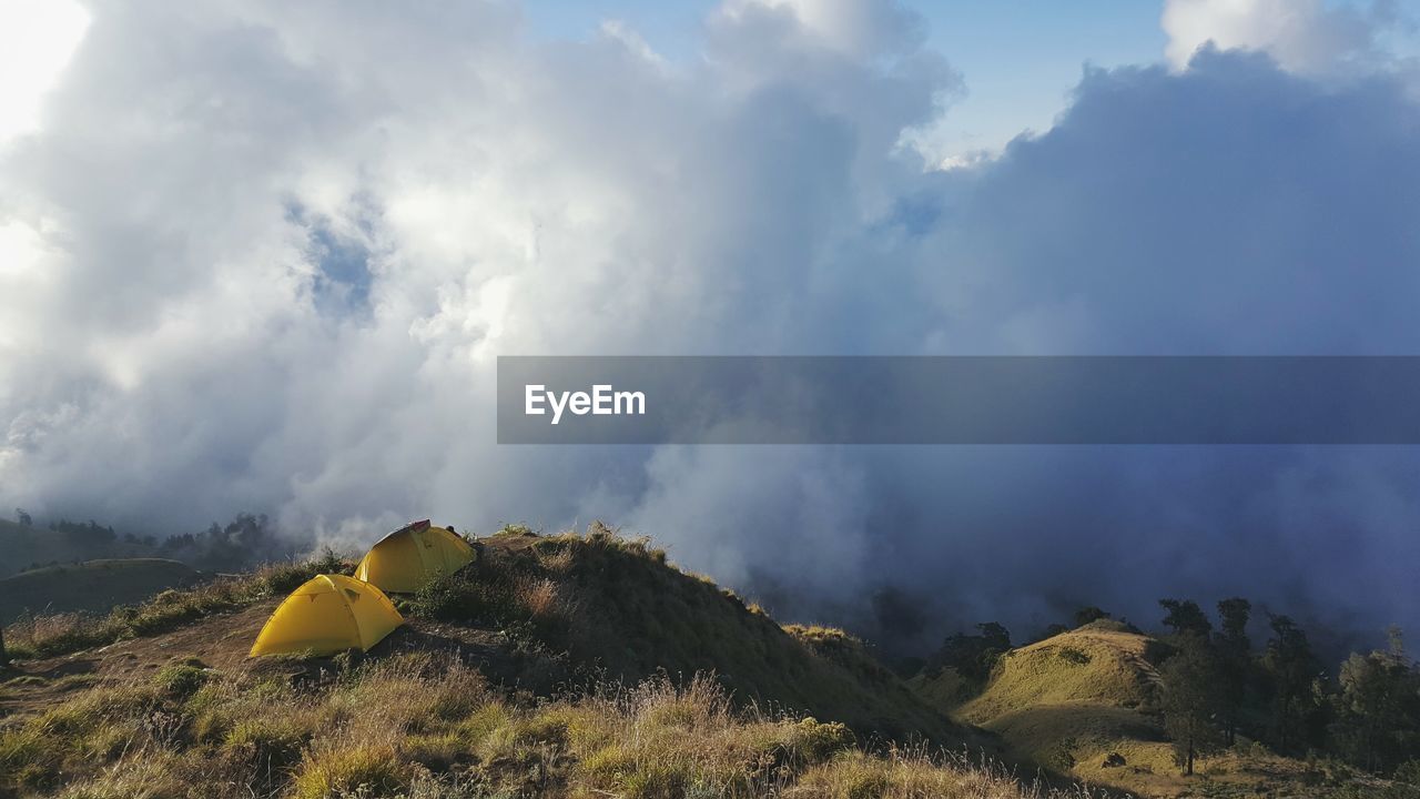 Tents on mountain against cloudy sky