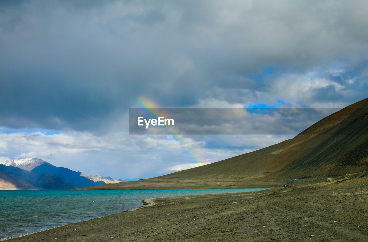 SCENIC VIEW OF RAINBOW OVER SEA AND MOUNTAINS