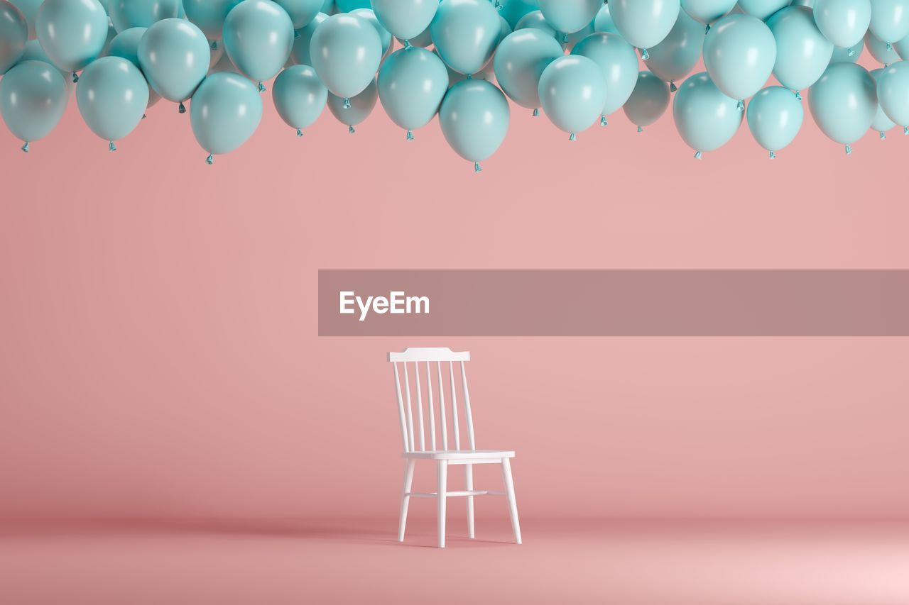 Balloons and chair against pink background