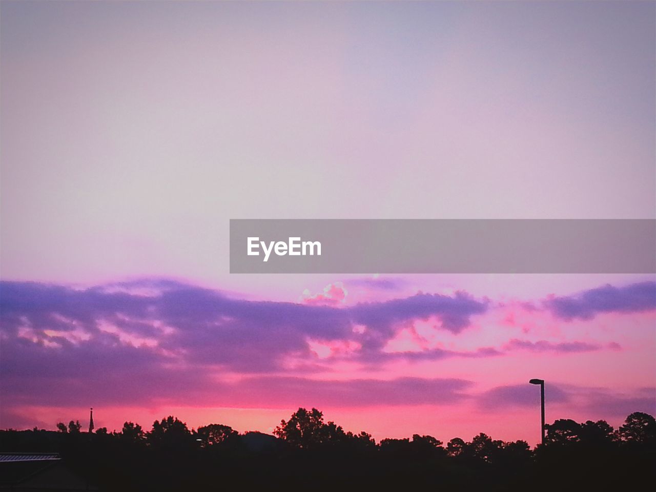 Silhouette trees against cloudy orange sky during sunset