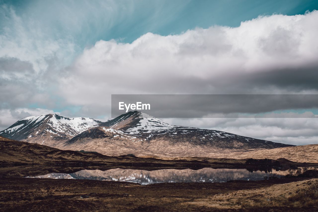 Scenic view of snowcapped mountains against cloudy sky