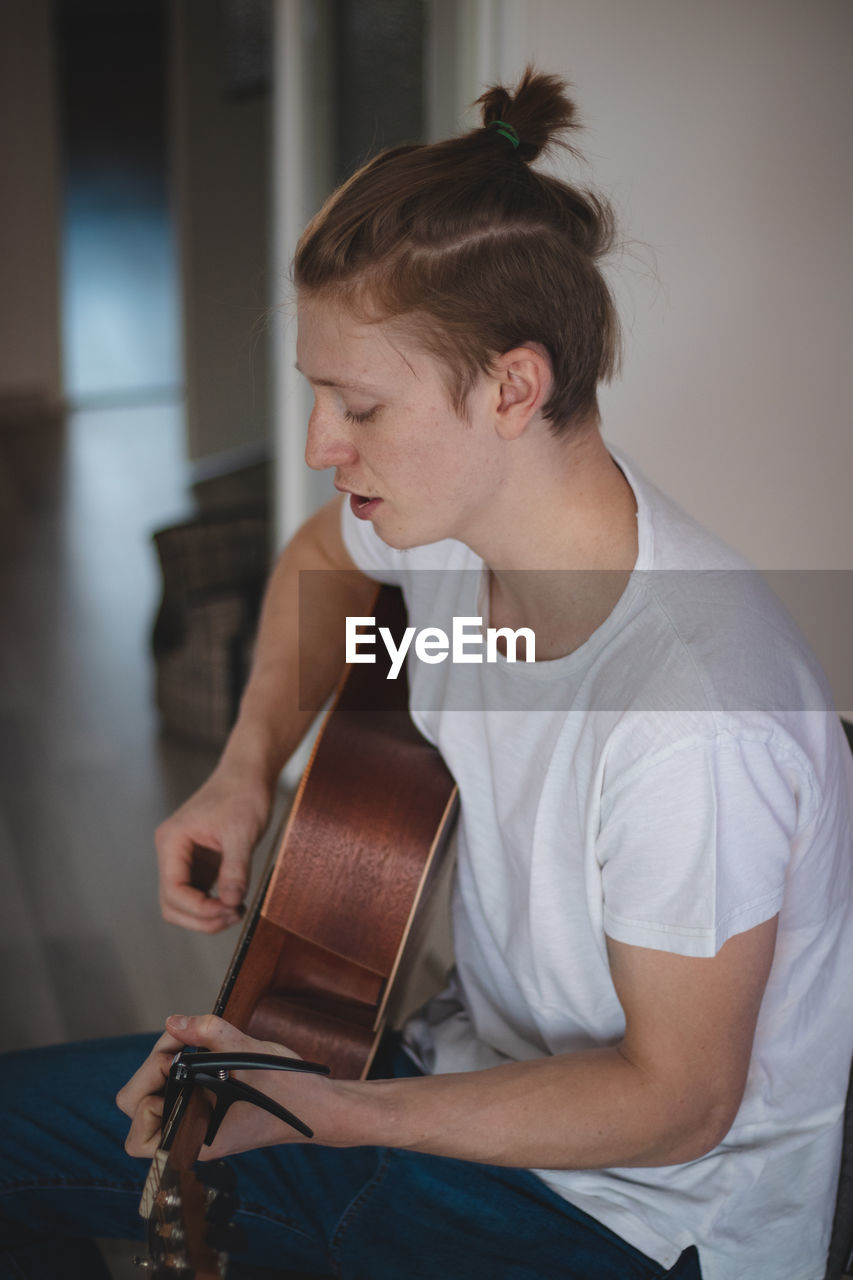 Dreamy look of a young blond singer with freckles sitting in the middle of a lighted room