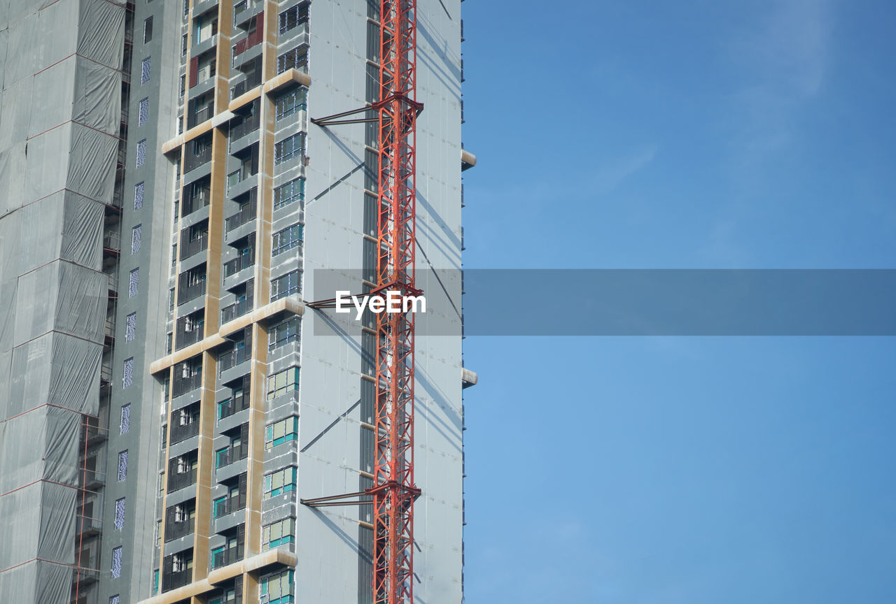 LOW ANGLE VIEW OF CRANE AND BUILDINGS AGAINST SKY