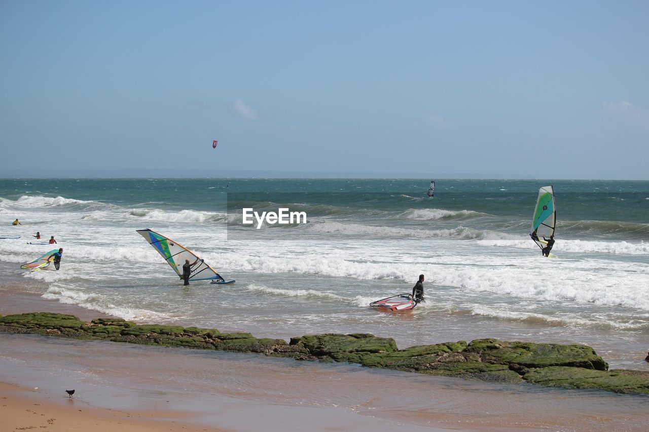 People windsurfing on sea against sky