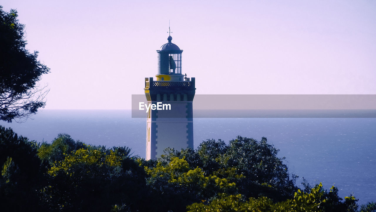         view of the beautiful cape spartel lighthouse that appears behind the trees  