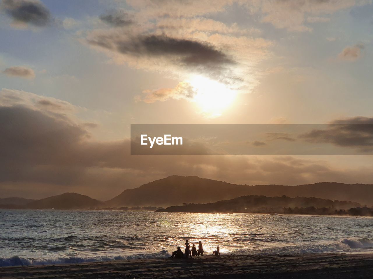 People on beach against sky during sunset