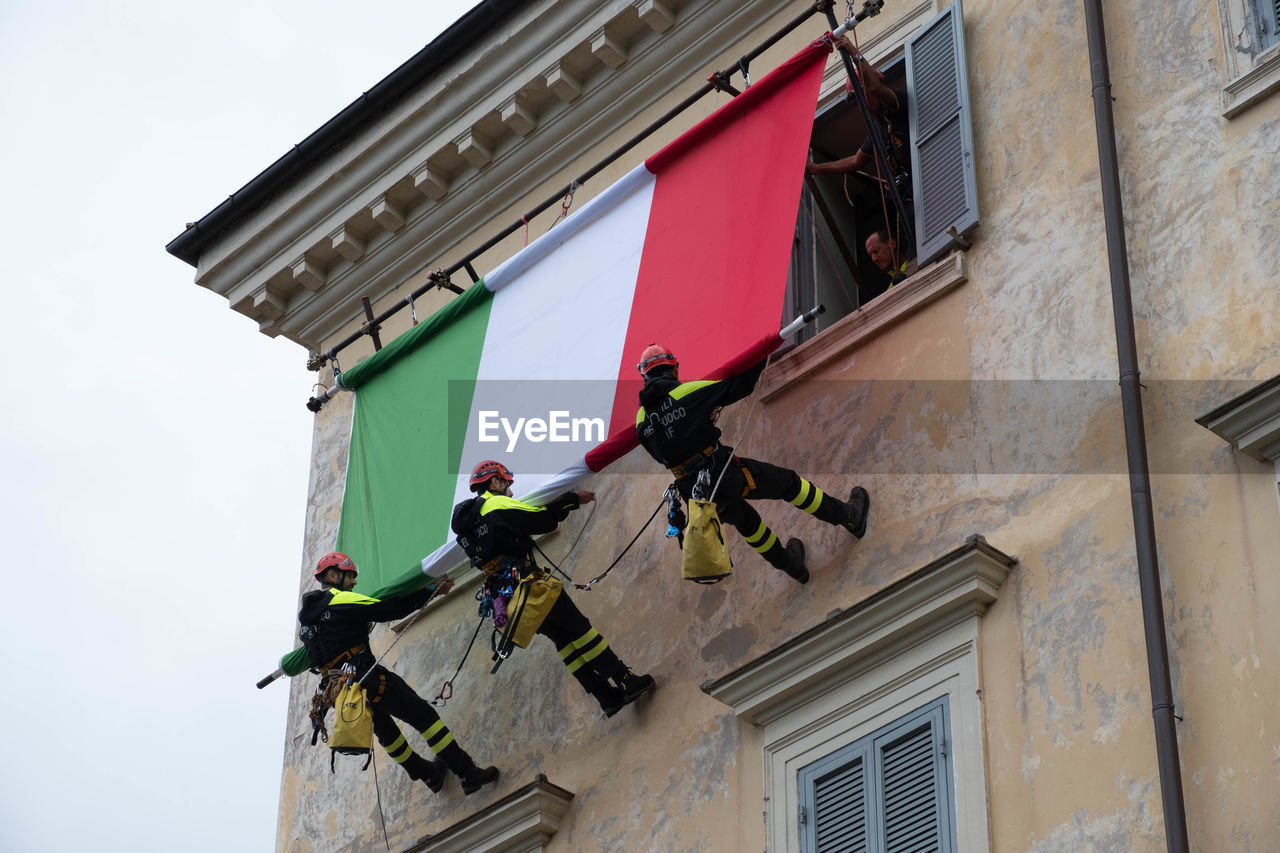 LOW ANGLE VIEW OF FLAGS HANGING OUTSIDE BUILDING AGAINST SKY