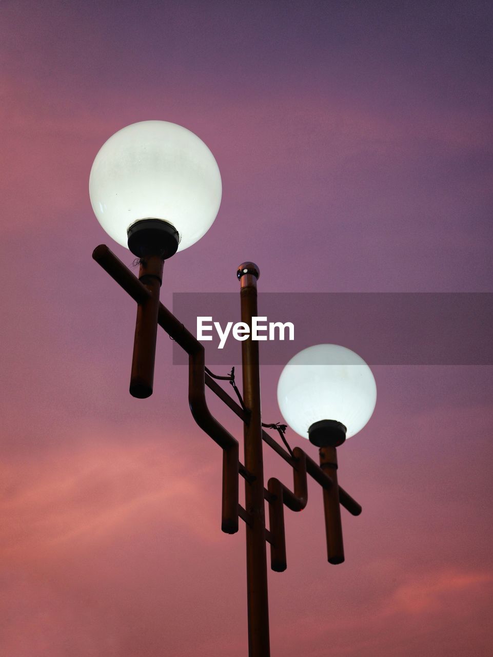 Low angle view of illuminated street light against sky at sunset