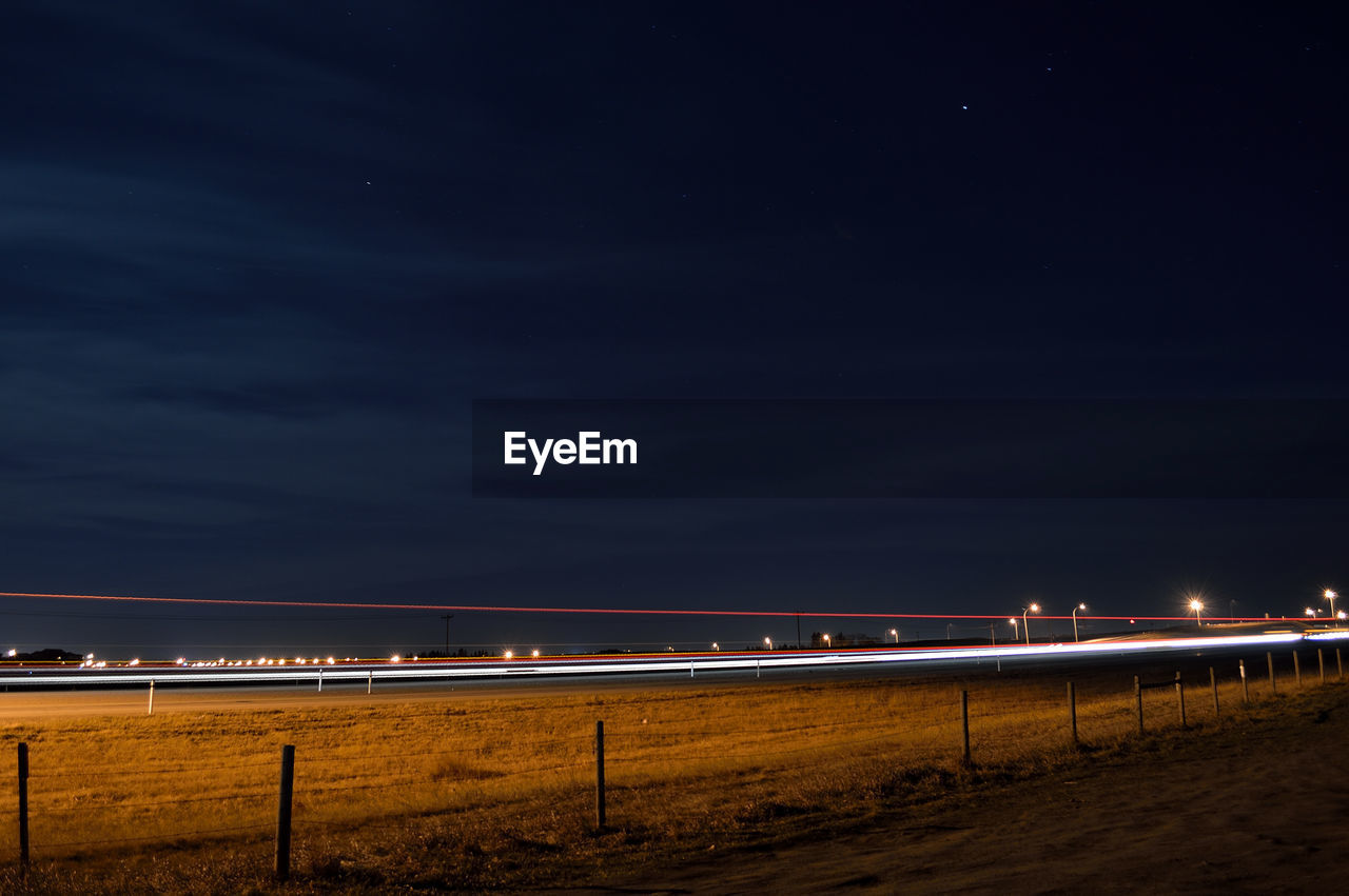 Light trails over field against sky at night