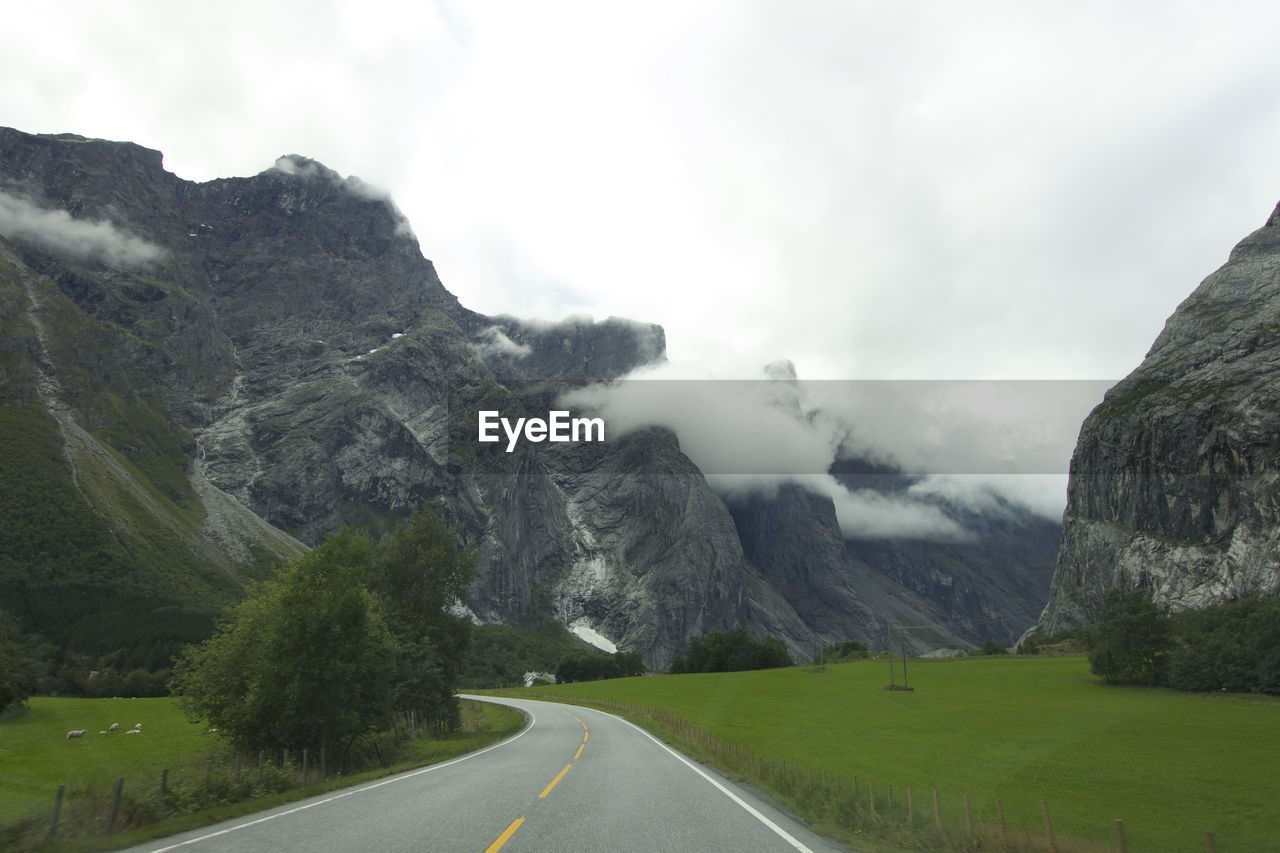 Road leading towards mountains against sky