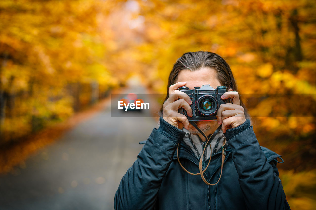 Photographer on autumn forest road