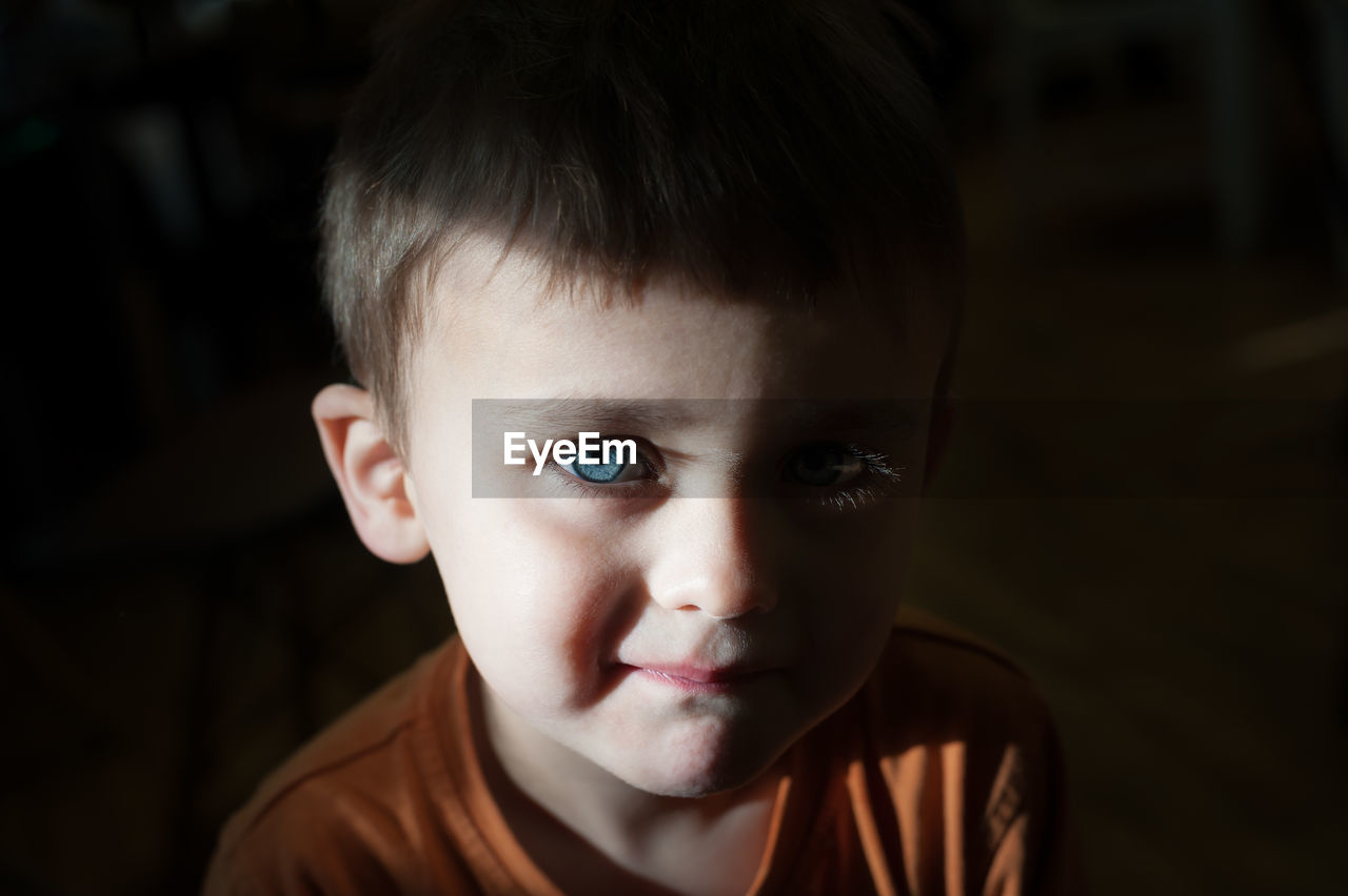 Close-up portrait of cute boy in darkroom