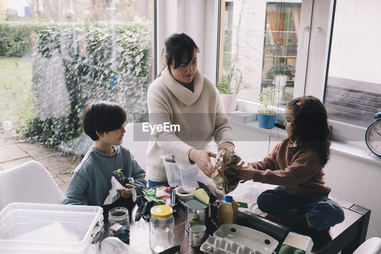 Woman separating waste with children at home