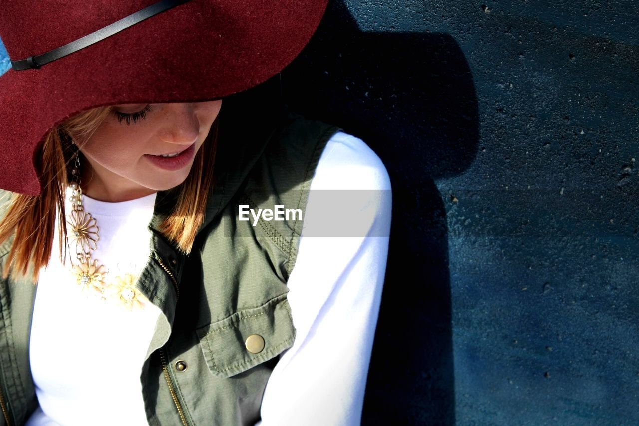 High angle view of young woman wearing hat while standing against wall