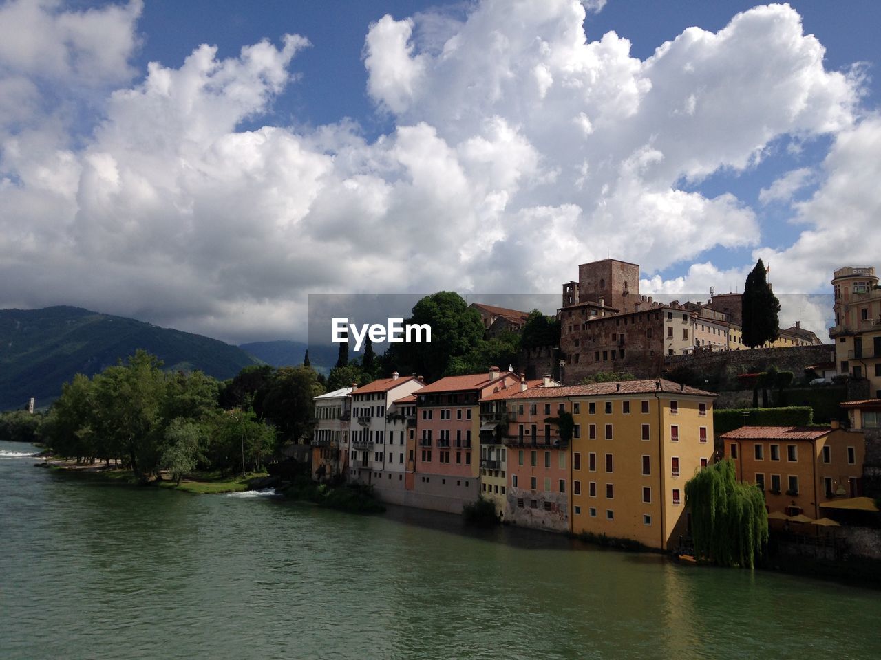 Buildings by river against sky