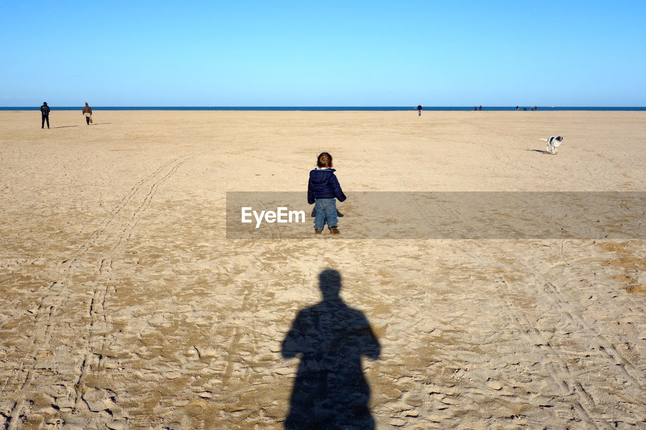 SILHOUETTE OF WOMAN ON BEACH AGAINST CLEAR SKY