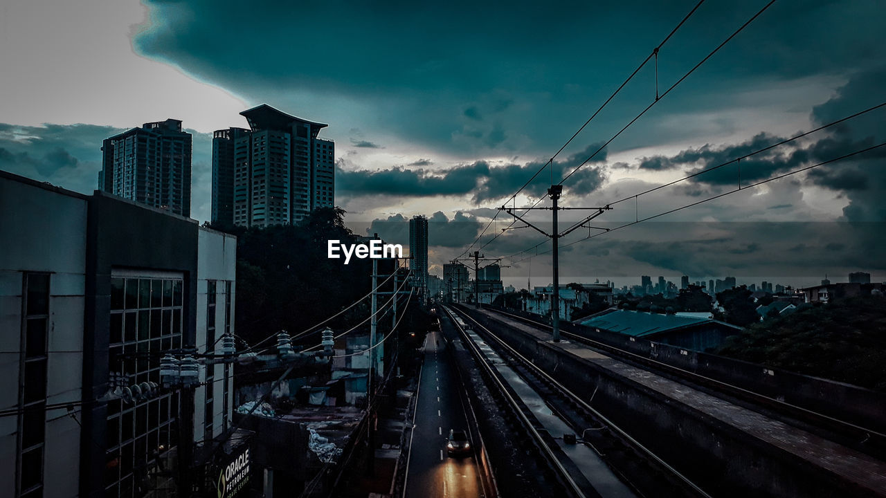 Road amidst buildings in city against sky