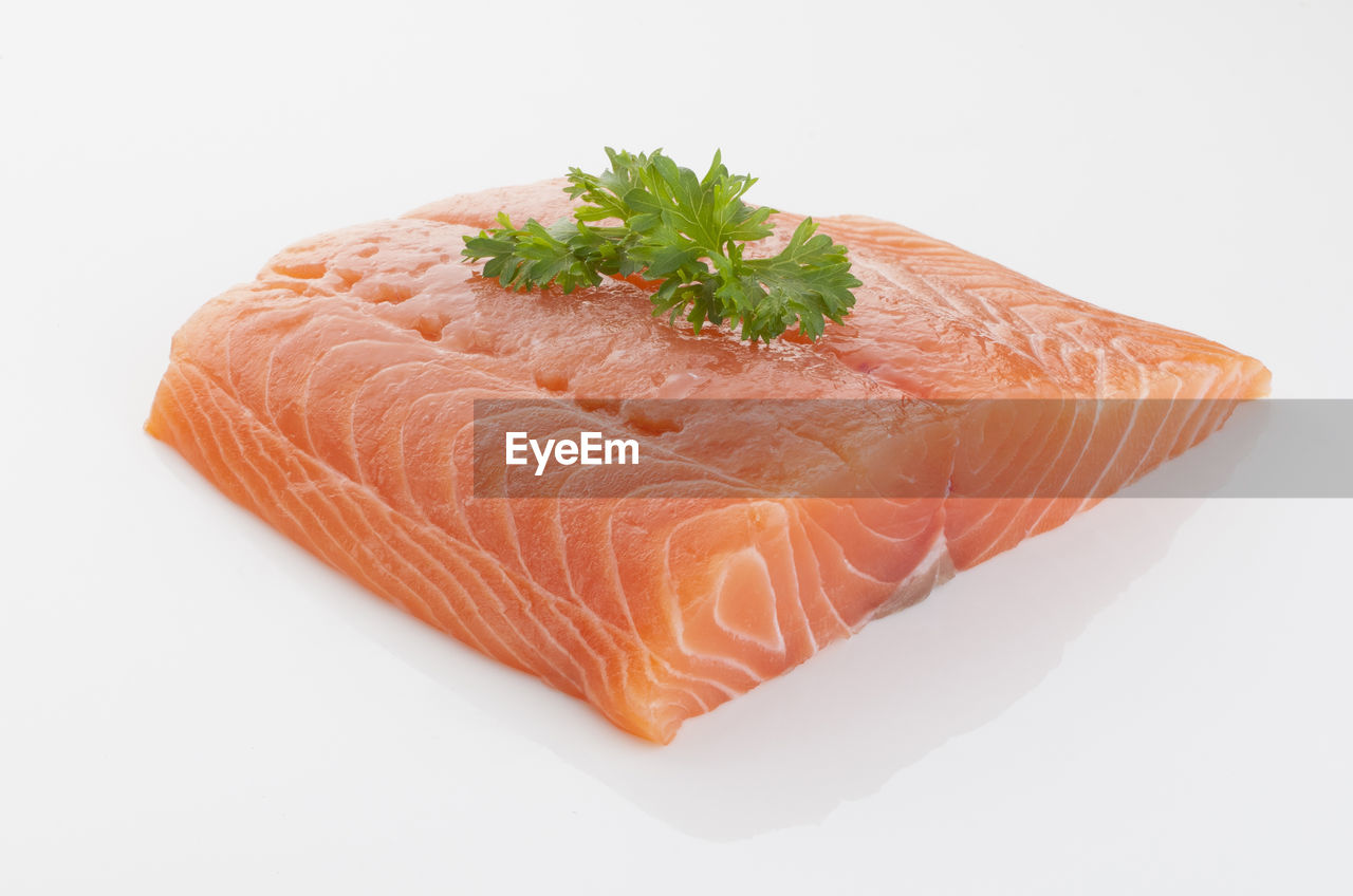 Close-up of raw seafood with herb over white background